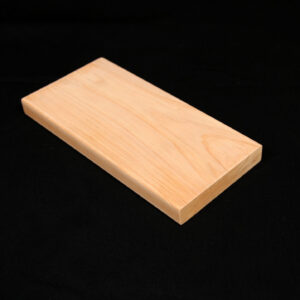 Cypress 1x4. Light-colored rectangular wooden plank with smooth edges and visible grain resting on a black fabric background.