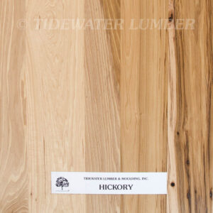 Hickory Flooring Hickory wood sample with vertical light-to-medium brown grain, darker streaks and knots at the right, and a white label near the bottom reading Tidewater Lumber & Moulding, Inc. HICKORY with a faint Tidewater Lumber watermark across the top.