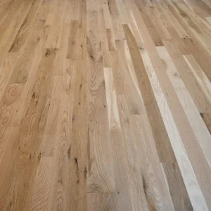 Euro White Oak Flooring Low-angle view of a light oak hardwood floor with staggered narrow planks, visible wood grain, knots, and natural color variation.