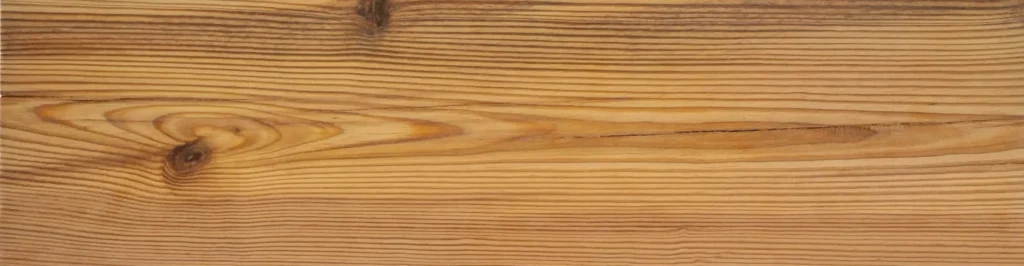 Vertical light-brown wooden plank showing pronounced parallel grain lines and two knots, one near the top center and one at mid-right.