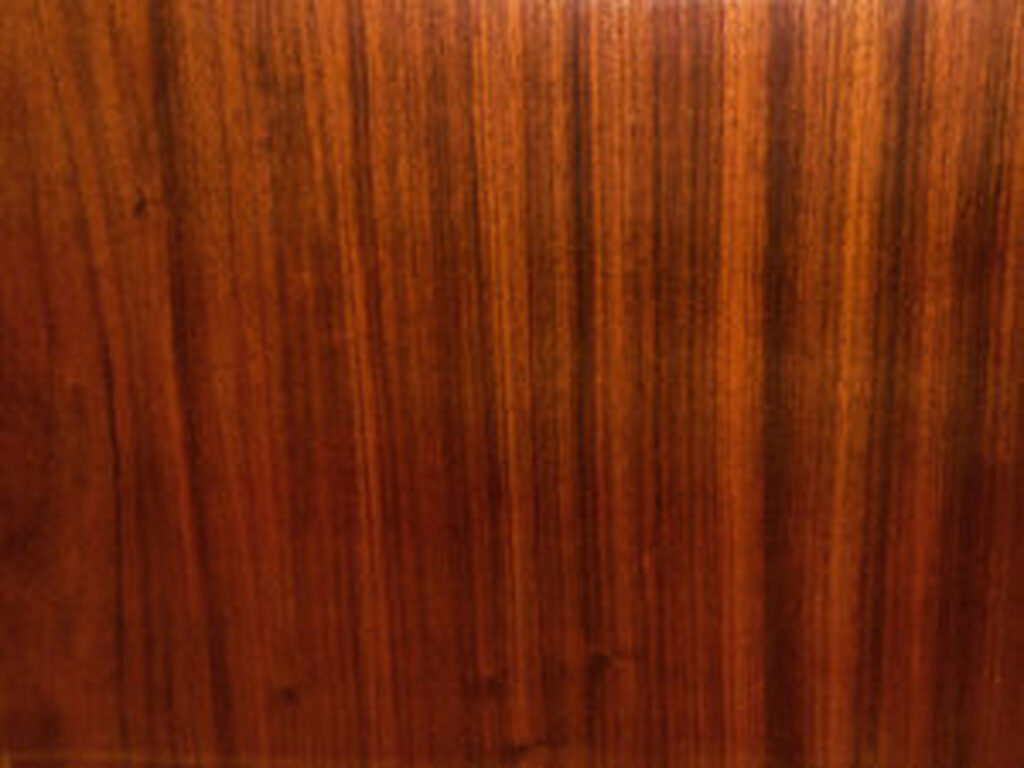 Close-up of a warm reddish-brown polished wood panel showing vertical grain lines and subtle knots.